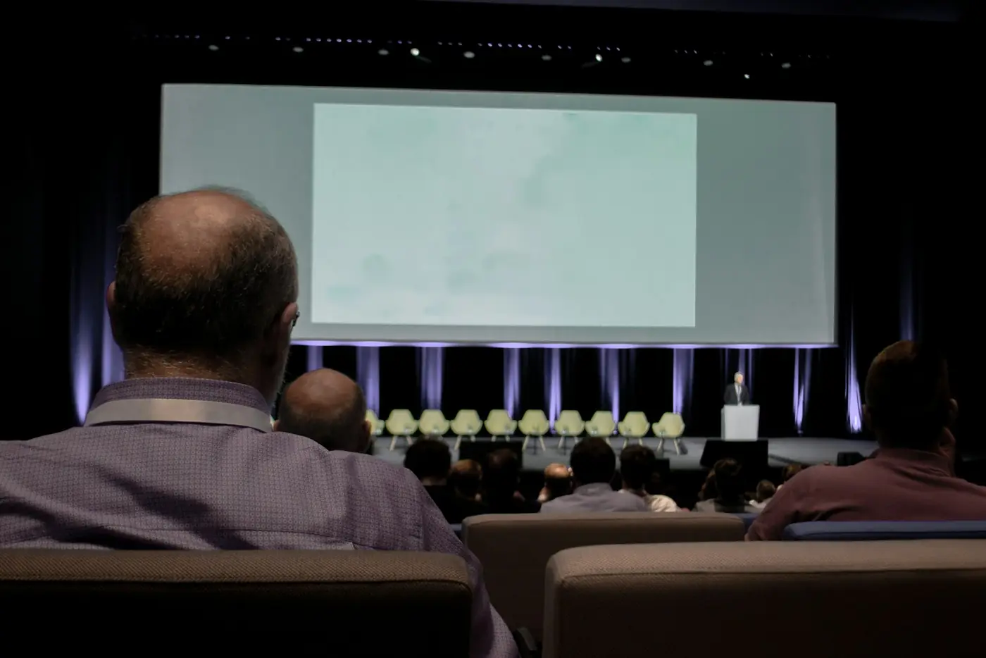 Audience seated in front of a projection screen in a conference hall