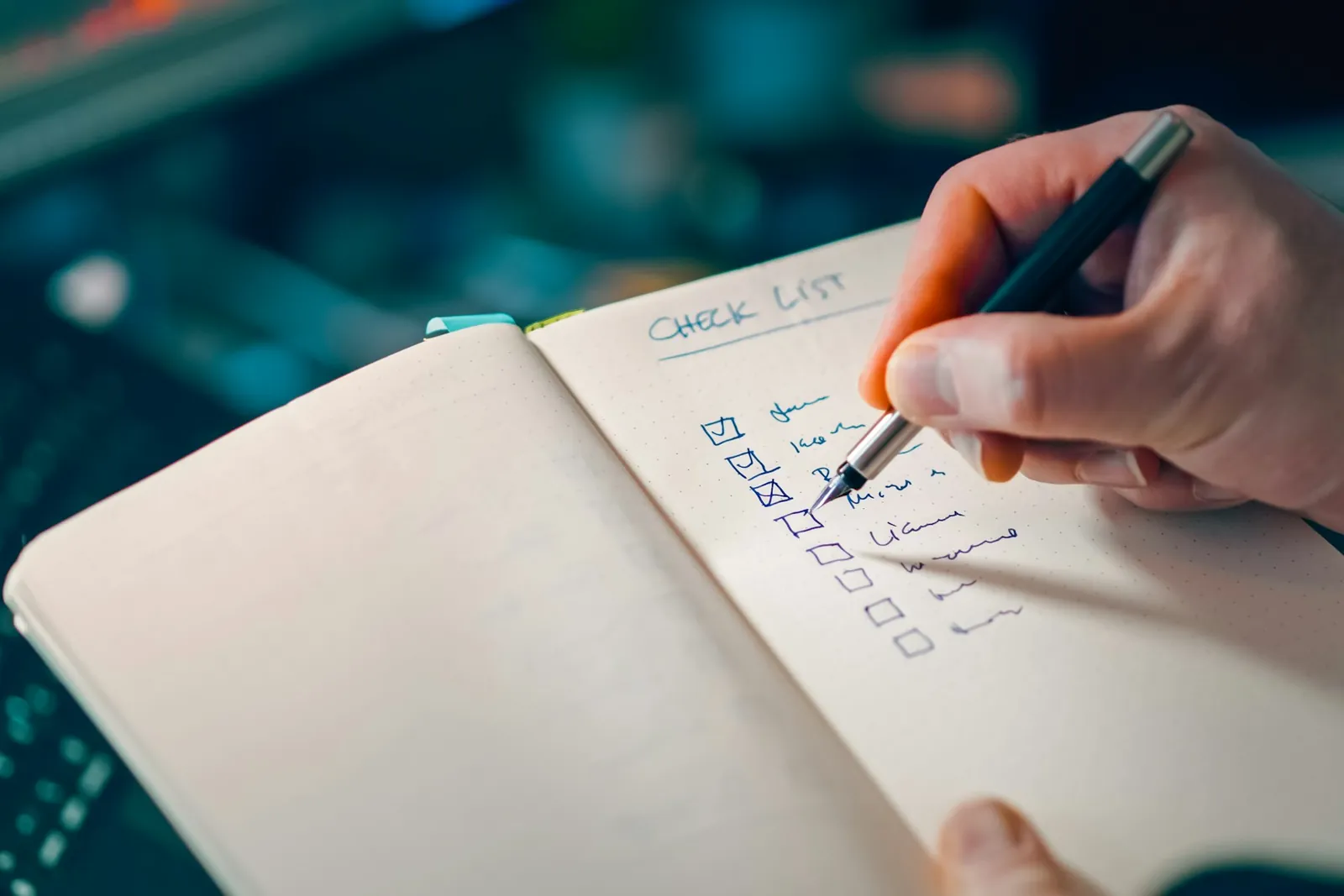Hand ticking items on a checklist in an open notebook