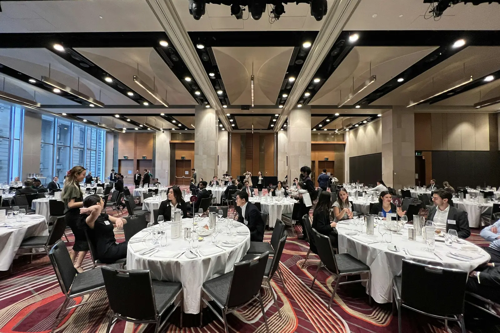 Round dining tables set up in a large hotel ballroom, with guests seated and staff moving between them