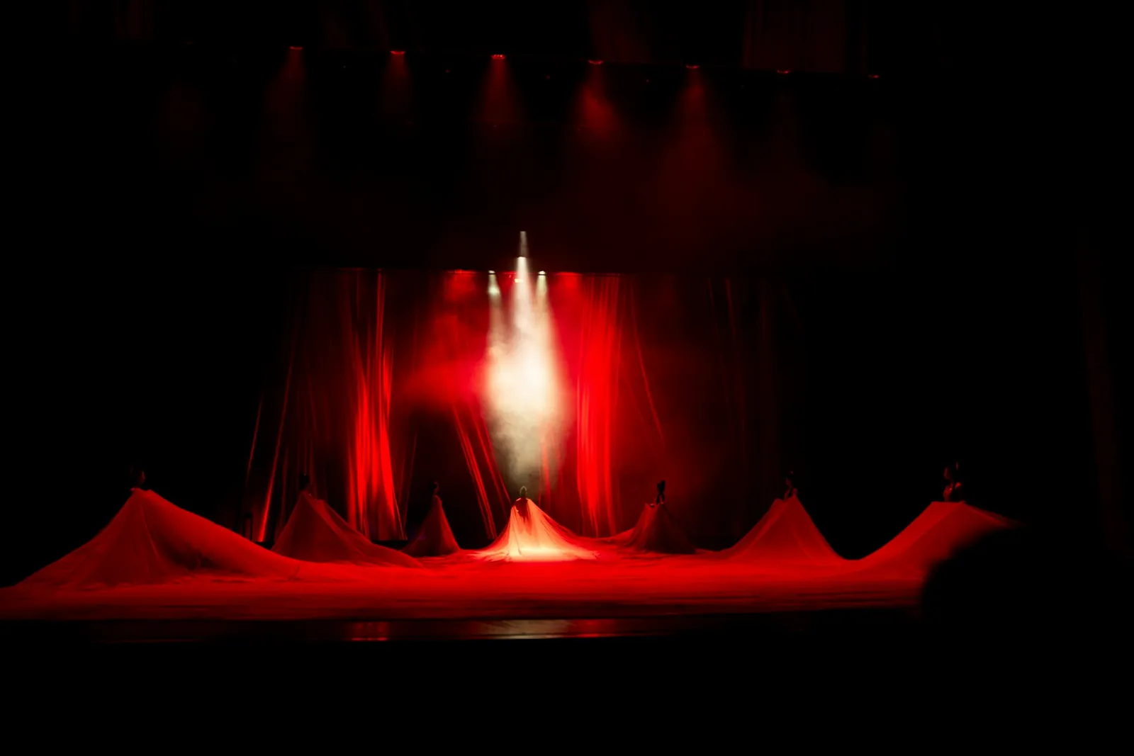 Stage with red drapes lit by a single spotlight through haze