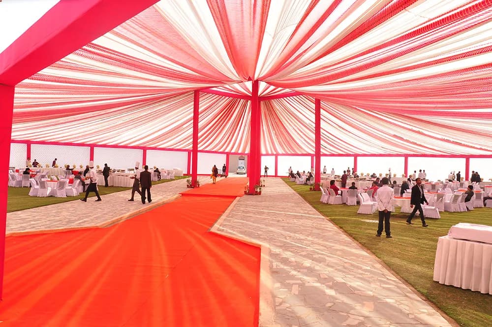 Red and white fabric-draped tent with banquet tables and a red carpet aisle