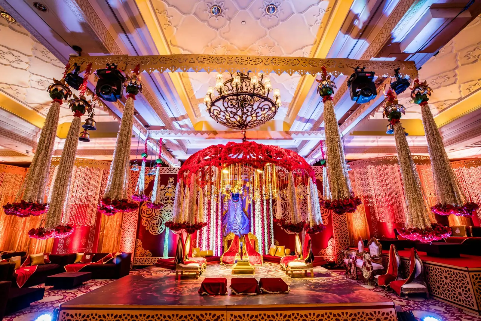 Decorated event hall with a chandelier, floral canopy stage and professional stage lighting