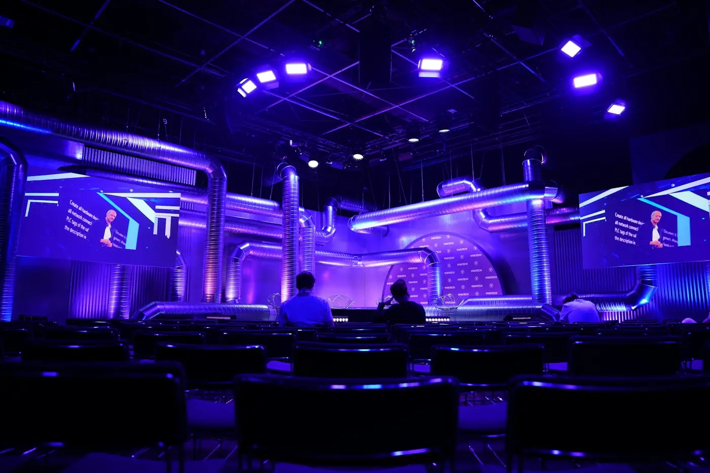 Stage set with purple lighting and large screens